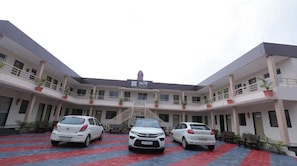 A building with a sign reading 'RESORT' and three cars parked in front. - Rushi Resort By ARDEA (Valsad)