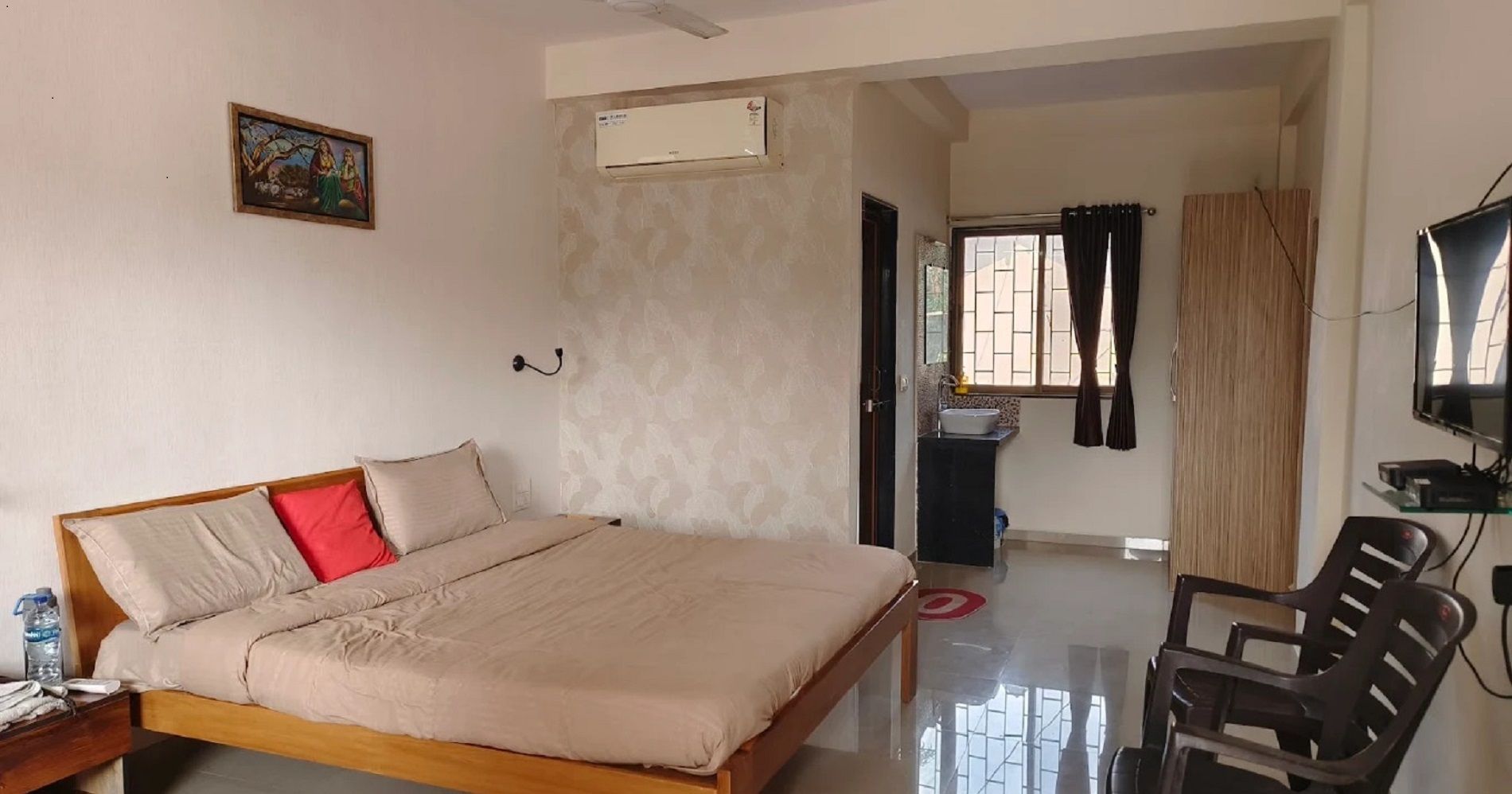A hotel room with a bed, a desk, a chair, a television, and a window with curtains.