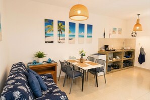 A modern living space with a sofa, dining table, chairs, and a kitchen area. - Charming Curaçao – Central, Private & Free Parking (Willemstad)