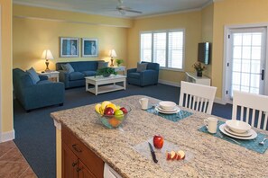A living room with a blue sofa set, a coffee table, and a kitchen area with a granite countertop. - Cozy 2-bedroom apartment in beautiful Hilton Head Island with AC (Hilton Head Island)