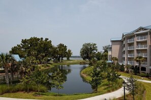 A residential building with multiple balconies, a pond, and surrounding greenery. - Cozy 2-bedroom apartment in beautiful Hilton Head Island with AC (Hilton Head Island)