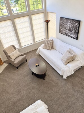 A room with a white sofa, a beige armchair, a round coffee table, and a floor lamp. - Close to Lakeview Golf Course (Meridian)