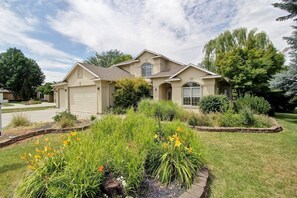 A single-story house with a garage, surrounded by a well-maintained garden with various plants and flowers. - Close to Lakeview Golf Course (Meridian)