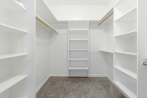 Ein begehbarer Kleiderschrank mit weißen Regalen und einer Holzleiter.