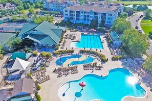 Un resort con varias piscinas, zonas de descanso y un edificio grande al fondo.