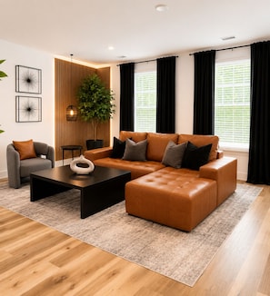 Ein modernes Wohnzimmer mit einem Ecksofa, einem Couchtisch, einem Beistelltisch und einer Topfpflanze.