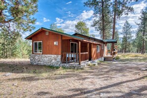 A wooden cabin with a stone foundation, surrounded by tall pine trees. - Cozy house on seven wooded acres near Hamilton (Hamilton)