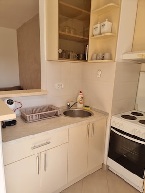 Een keuken met een spoelbak, fornuis en kastjes.