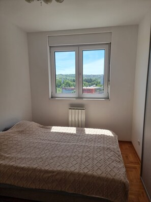 Een slaapkamer met een bed, een raam en een radiator.
