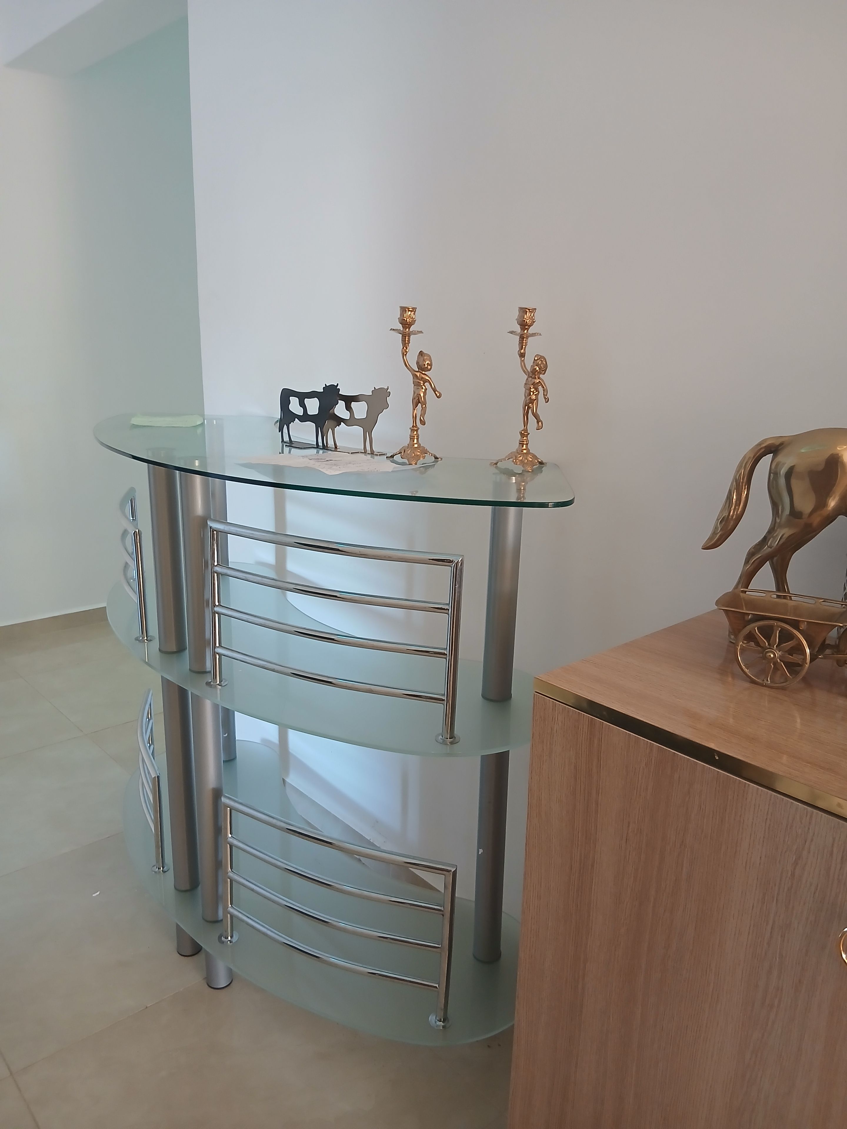 Un bureau moderne, composé de plusieurs niveaux et fait de verre et de métal, avec un meuble en bois placé à côté.