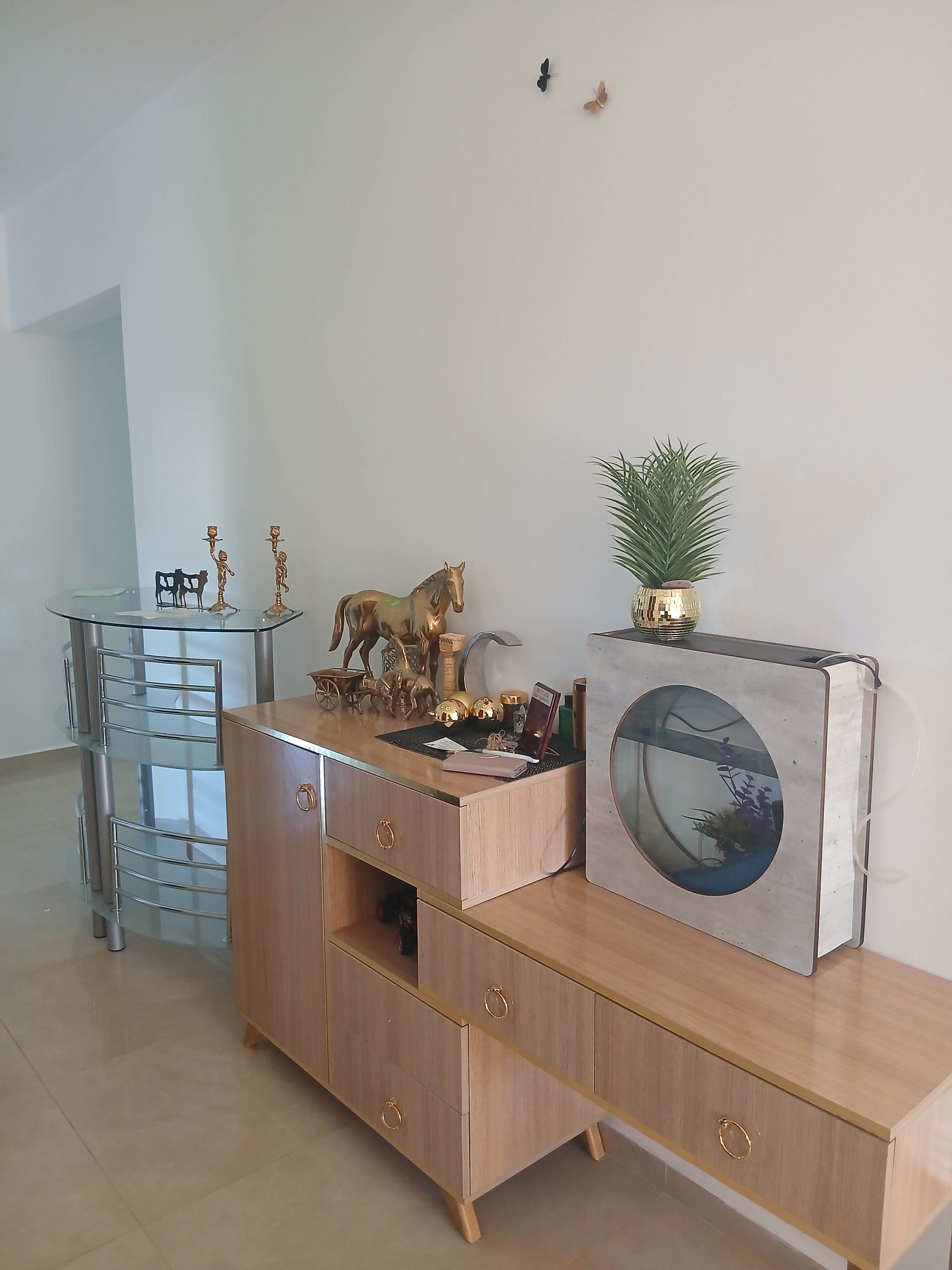 Ein modernes Wohnzimmer mit einem Holzkasten, einem Glastisch, Dekoration und einem Aquarium.