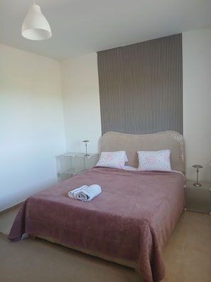 Une chambre à coucher avec un lit, une table de chevet, une lampe et un luminaire suspendu.