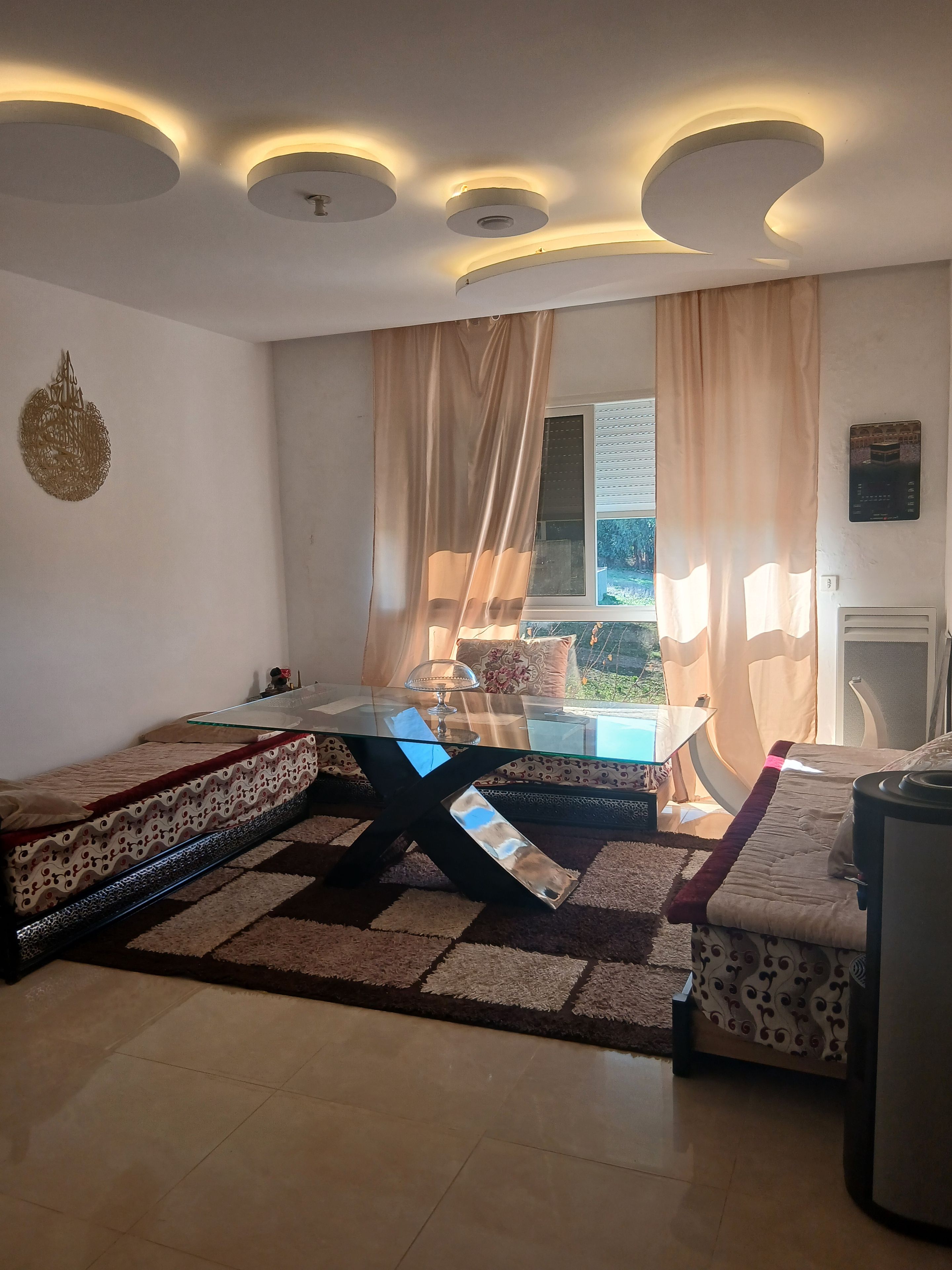 Un salon comprenant une table basse avec un plateau en verre, un canapé et un lit avec une literie à motifs.