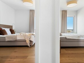 Ein modernes Schlafzimmer mit Bett, Vorhängen und Blick ins Freie.
