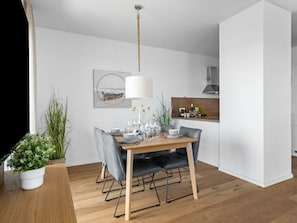 Een moderne eetruimte met een houten tafel, gestoffeerde grijze stoelen en een hanglamp.