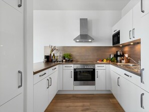 Een moderne keuken met witte kasten, roestvrijstalen apparatuur en een houten aanrecht.