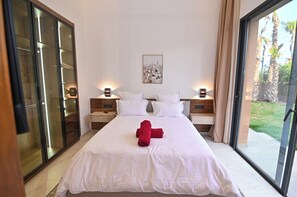 A hotel room with a large bed, a cityscape artwork on the wall, and a sliding glass door to the outdoors. - The oasis marakech ,                 A Beautiful villa in marakech (Marrakech)