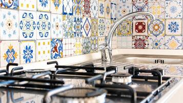 A kitchen with a gas stove, a sink, and a tiled backsplash with various patterns.