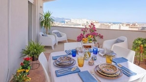 Mesa de comedor para dos en un balcón con vista despejada al paisaje urbano.