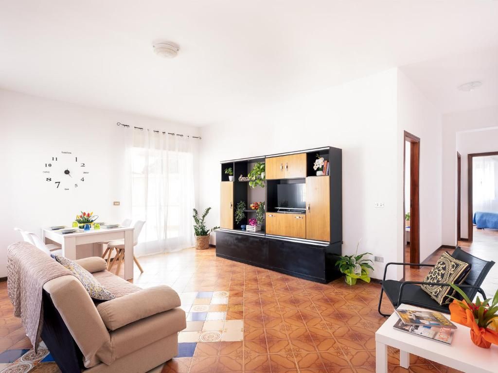 A modern living room with a sofa, a coffee table, a TV stand with cabinets, and a dining area with a table and chairs.