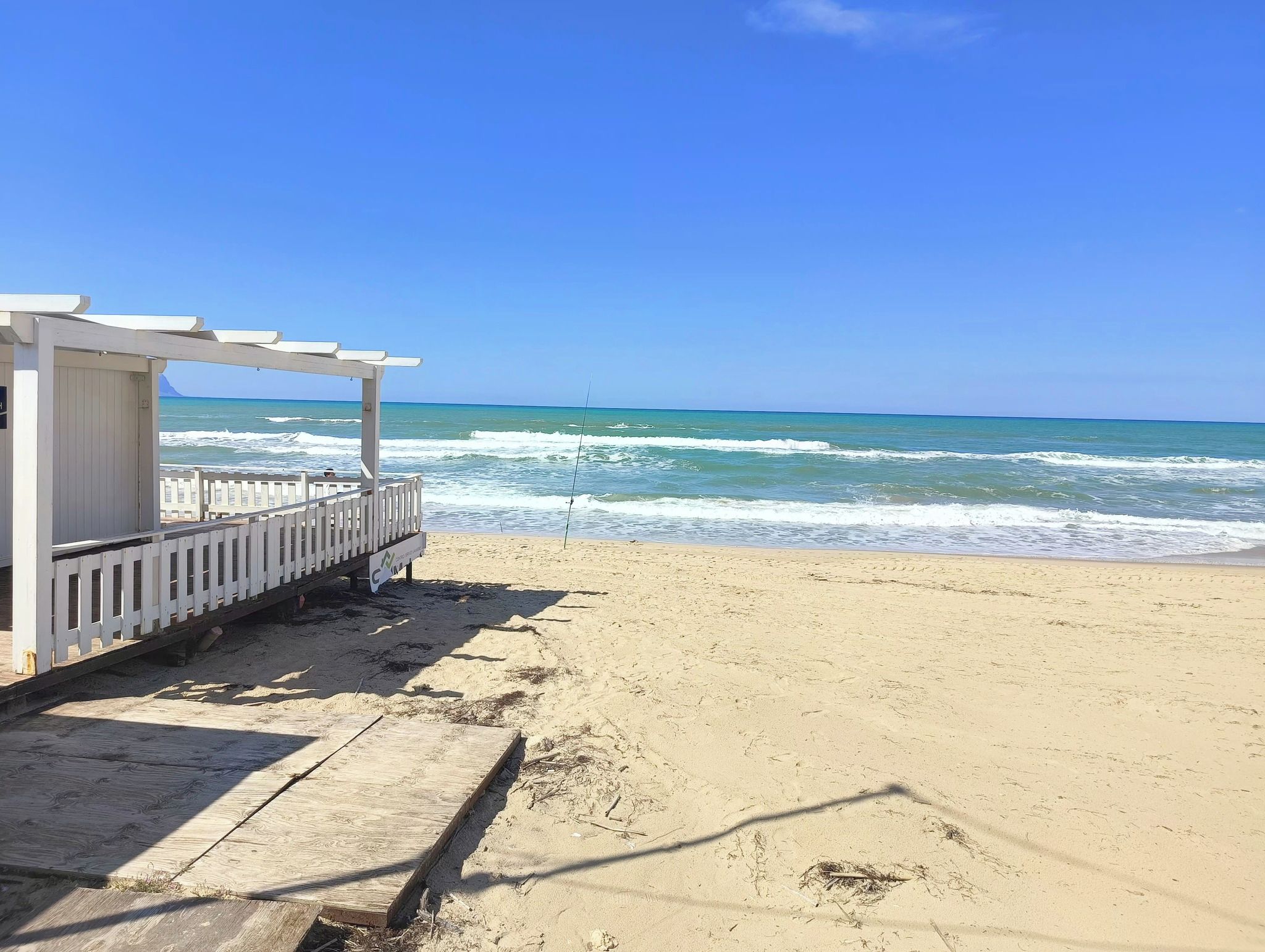 A beach with a wooden structure, possibly a lifeguard station, and the ocean in the background.