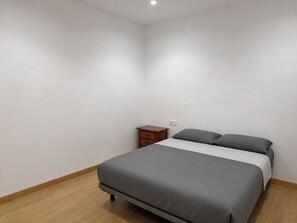 A bedroom with a bed, a nightstand, and a wall socket. - Beautiful 4-Bedroom Condo Near Barcelona Cathedral (catalunya)