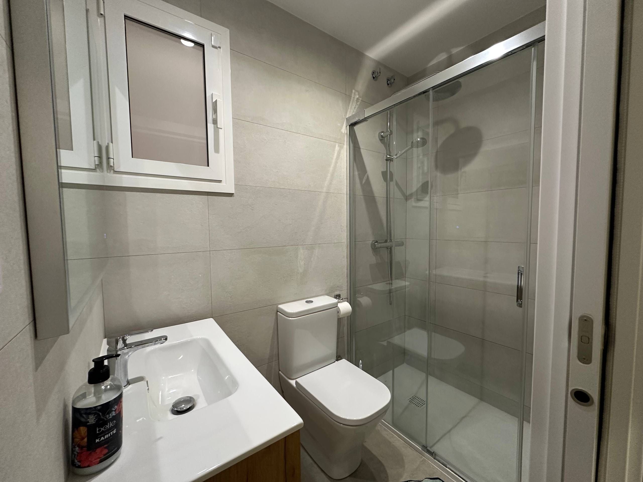 Un bagno con lavandino bianco, WC e cabina doccia in vetro.
