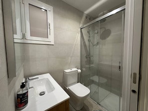 A bathroom with a white sink, toilet, and glass-enclosed shower. - Beautiful 4-Bedroom Condo Near Barcelona Cathedral (catalunya)