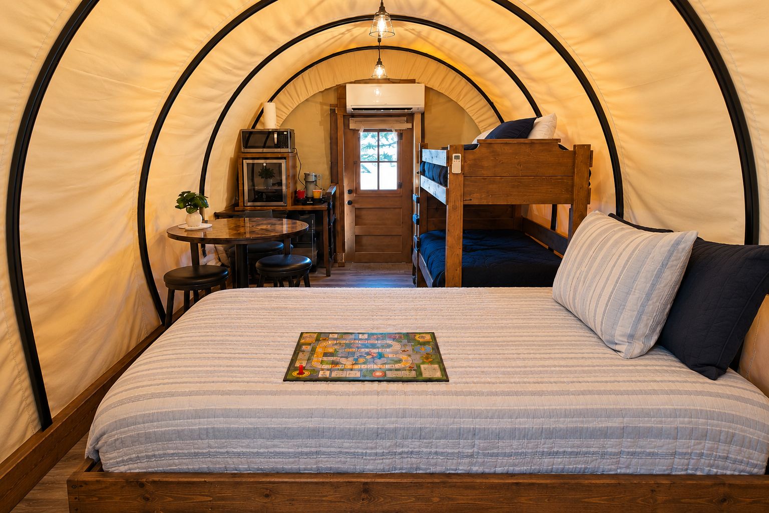 A cozy tent with a bunk bed, a small dining area, and a microwave.