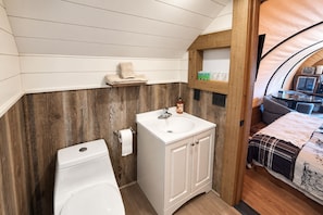 Ein kleines Badezimmer mit Waschbecken, Toilette und Wandverkleidung aus Holz.