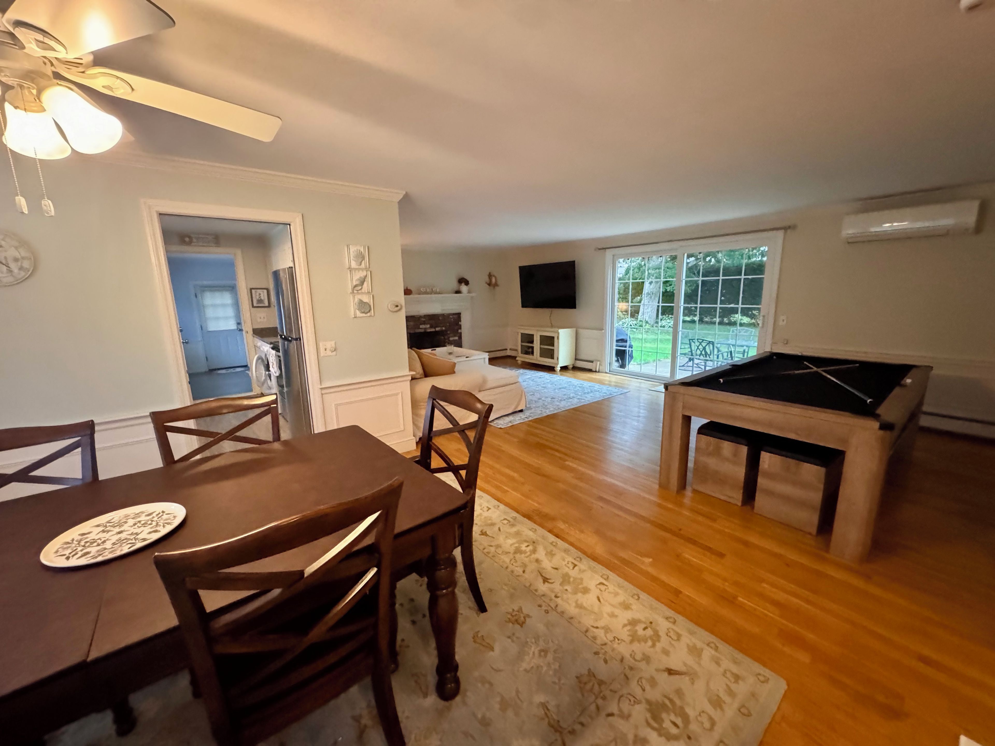 A spacious living area with a pool table, a dining table with chairs, and a sofa.