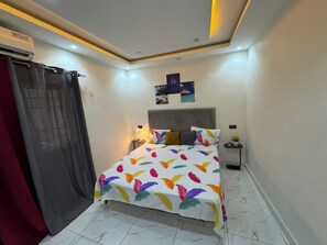 A bedroom with a bed, nightstands, a wall-mounted air conditioner, and a ceiling light fixture. - 6-bedroom apartment in superb Dakar with cool AC comfort (Dakar)