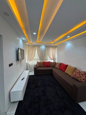 A modern living room with a sectional sofa, a flat-screen TV, and a white console table. - 6-bedroom apartment in superb Dakar with cool AC comfort (Dakar)