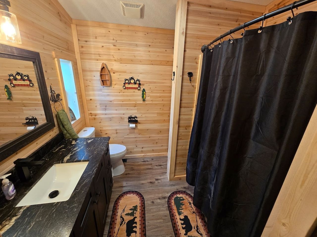 Un baño con detalles de madera que incluye lavamanos, inodoro y cortina de ducha.