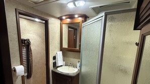 Een kleine badkamer met toilet, wastafel en douche.
