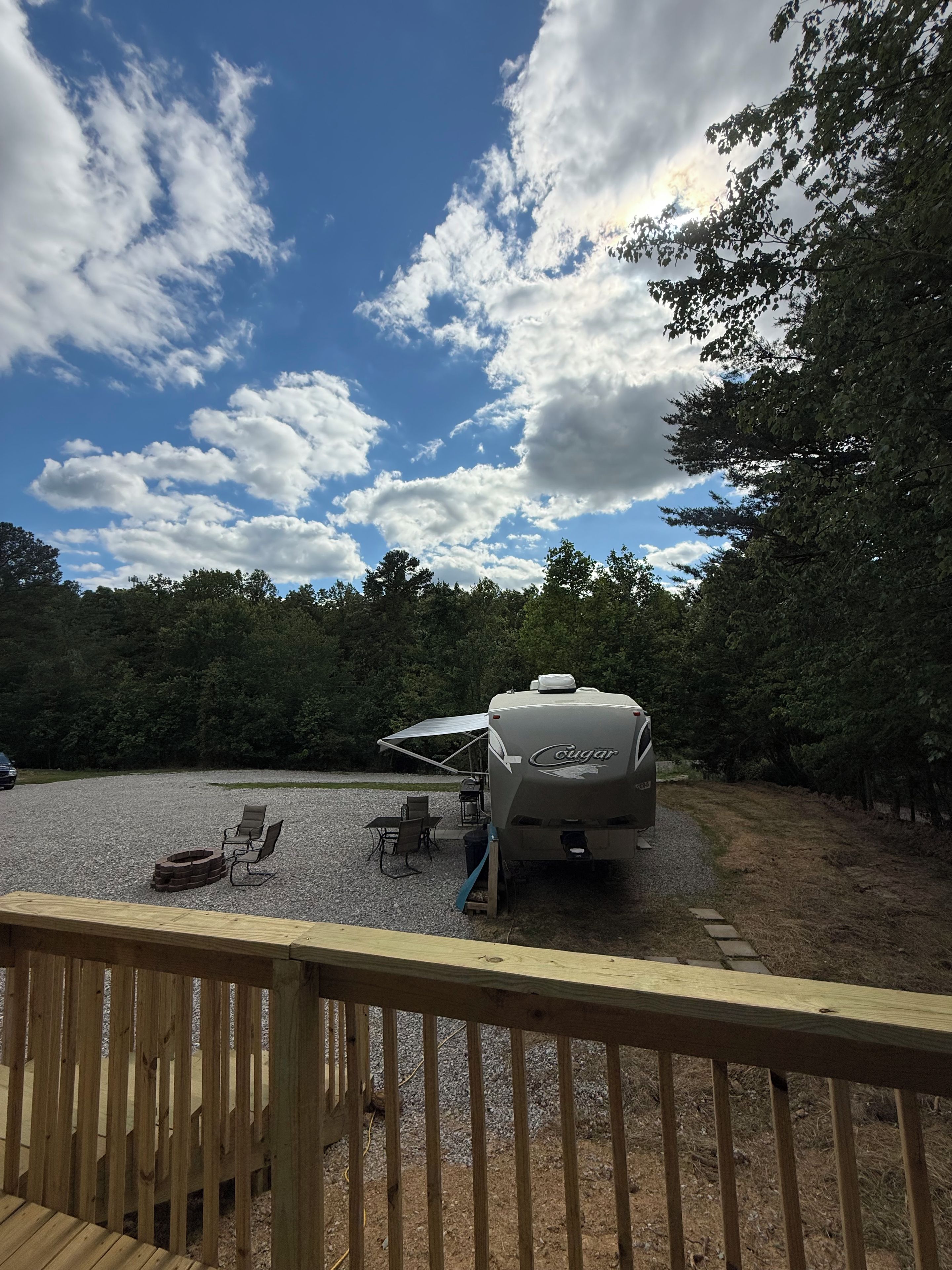 A campground with a covered RV area, outdoor seating, and a gravel ground.