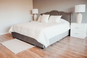 A neatly made bed with a grey headboard and white bedding, flanked by white nightstands with lamps and a vase on each. - Creekside Peaceful retreat Near Chicopee, 401 & YKF airport (Kitchener)