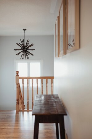 A wooden bench in a hallway with a ceiling light fixture and a door in the background. - Creekside Peaceful retreat Near Chicopee, 401 & YKF airport (Kitchener)