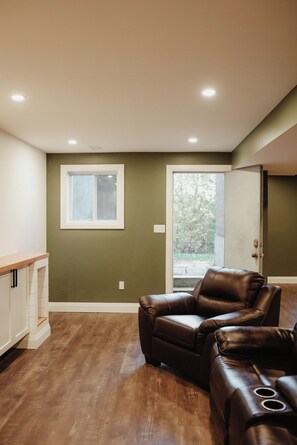A room with a brown leather sofa, a window, and a door leading outside.