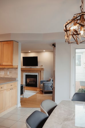 A modern kitchen with wooden cabinets, a built-in TV, and a fireplace.