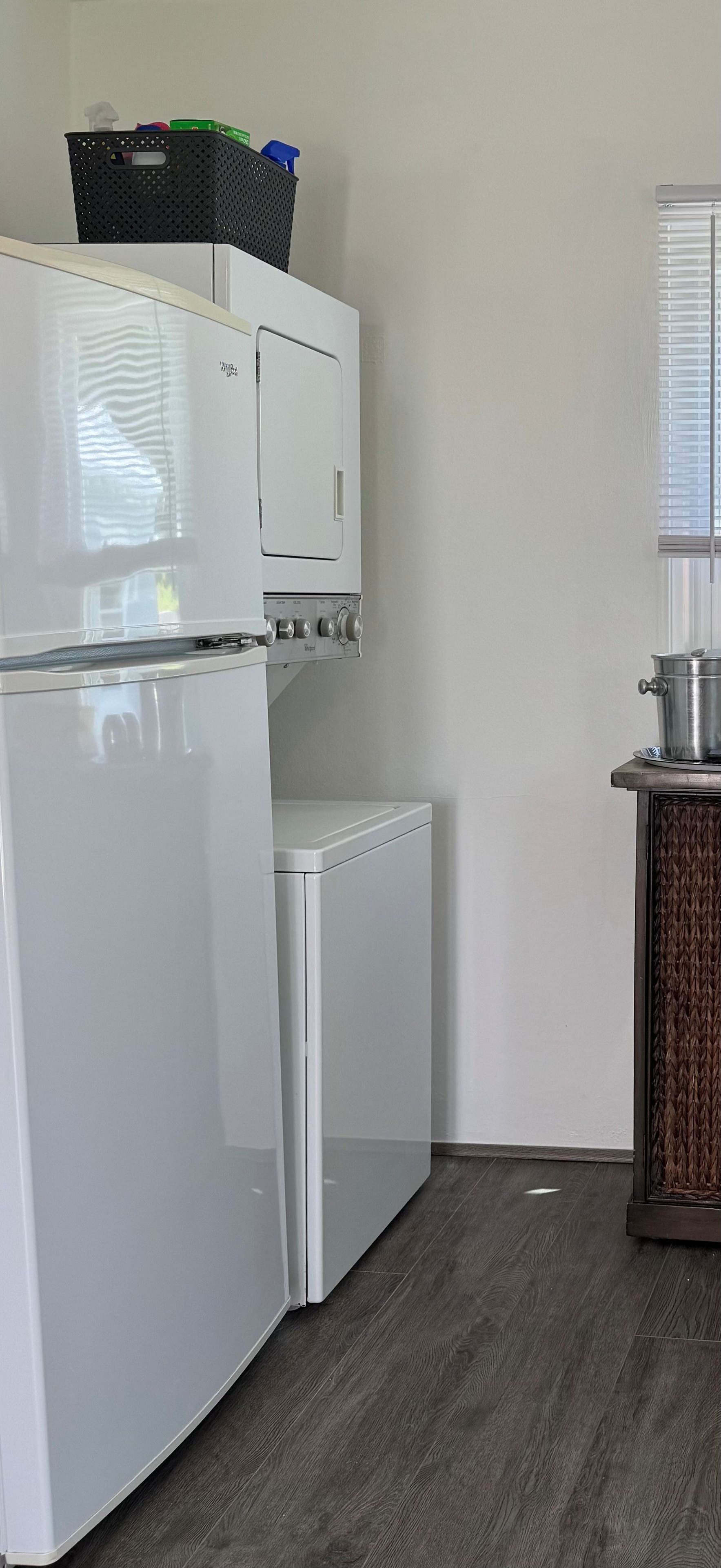 Eine kleine Küche mit Kühlschrank, Waschmaschine und einem Schrank mit einem Topf.