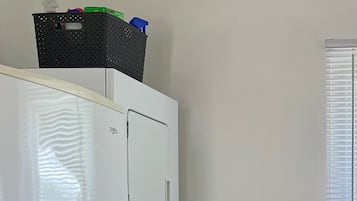 Eine kleine Küche mit Kühlschrank, Waschmaschine und einem Schrank mit einem Topf.