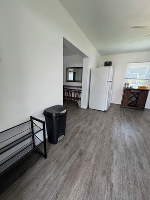A modern kitchen with a white refrigerator, a black trash bin, and a metal rack. - Fabulous large studio cottage with AC in charming Smiths (Smiths)
