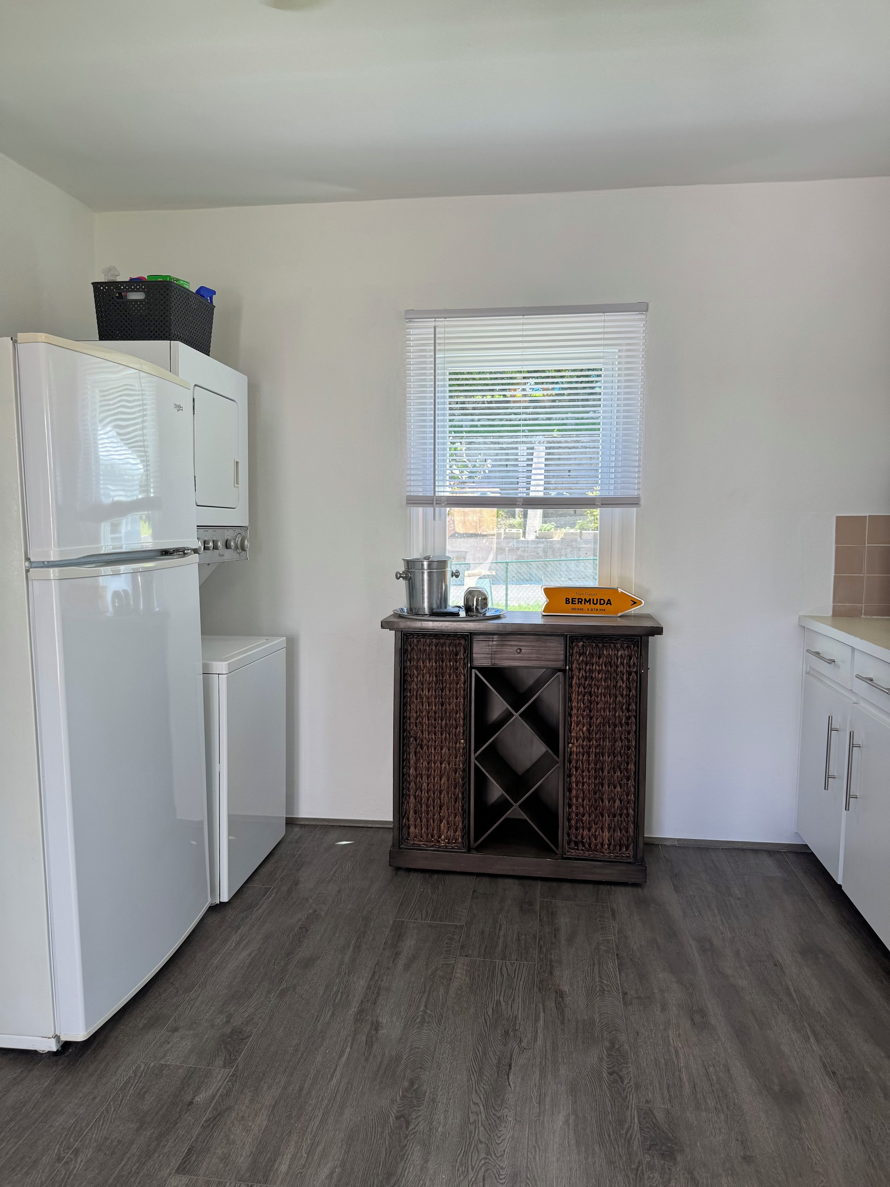 Una cocina con refrigerador, pileta y ventana con persianas.