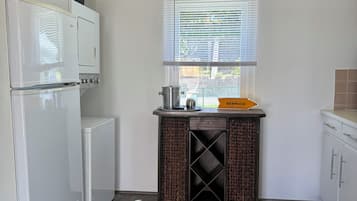 Una cocina con refrigerador, pileta y ventana con persianas.