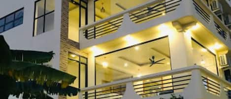Un edificio de varios pisos con balcones, ventanas amplias y asientos al aire libre.