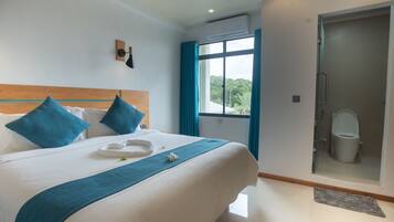 Habitación de hotel con cama, ducha y ventana con cortinas.
