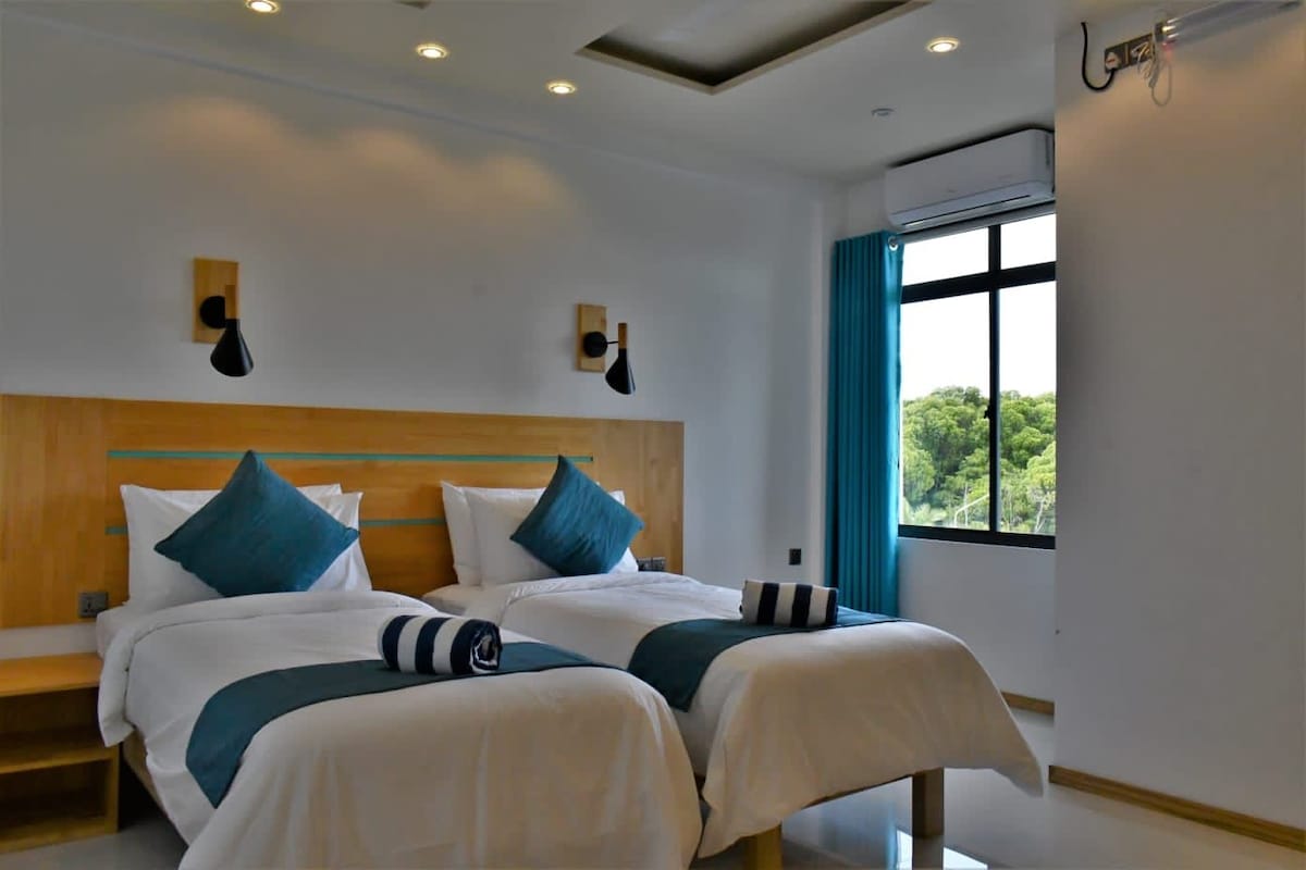 A double bed with a wooden headboard, two bedside tables, and a window with curtains.