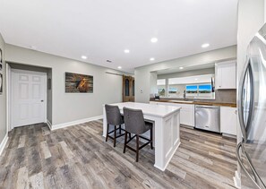 Een moderne keuken met een centraal eiland, barkrukken en een koelkast van roestvrij staal.