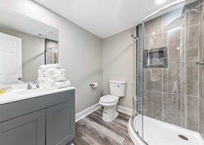 A modern bathroom with a shower, toilet, and vanity. - Bay-view 5BR Gulf Shores Home, Sleeps 12, and Easy Beach Access (Gulf Shores)